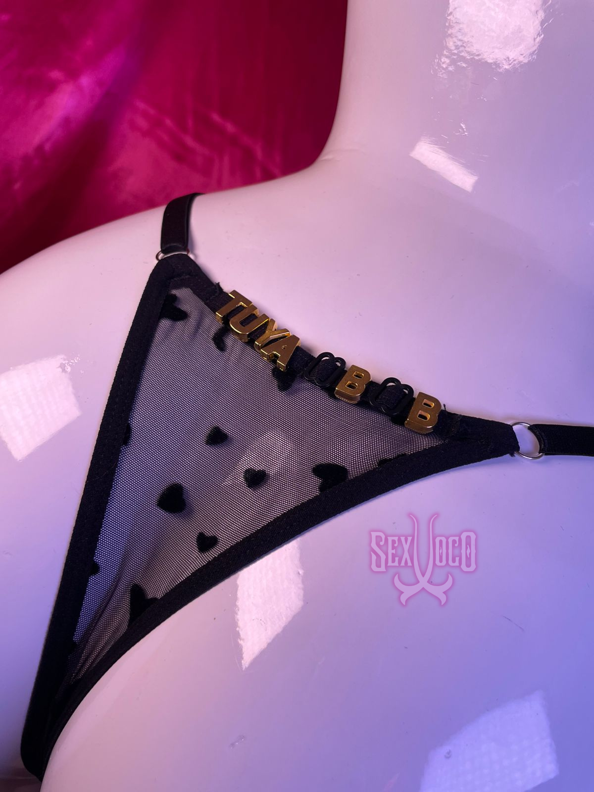 Tanga negra transparente con corazones y frase personalizada TUYA BB en letras doradas.